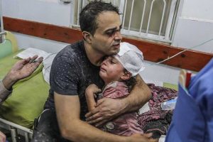 Seorang ayah sedang menenangkan anaknya yang menjadi mangsa kekejaman Zionis Israel dengan memeluk erat anaknya itu.