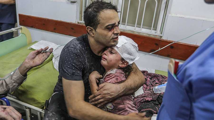 Seorang ayah sedang menenangkan anaknya yang menjadi mangsa kekejaman Zionis Israel dengan memeluk erat anaknya itu.